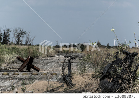 Destroyed road with barbed wire and tank traps symbolizing war, defense and military conflict zone 130898873