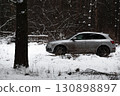 SUV car parked in snowy winter forest, surrounded by trees, symbol of travel, adventure, and cold season nature 130898897