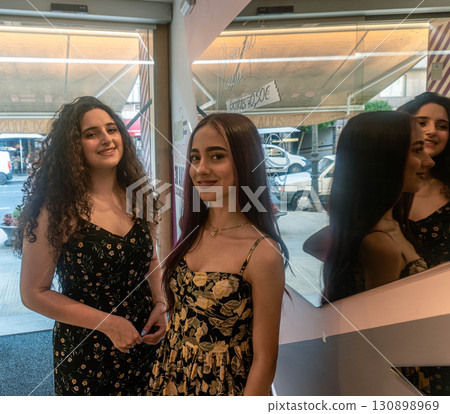 Two young women posing in ice cream parlor in sundresses 130898969