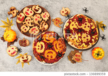 Halloween food concept, holiday meal idea for kids and adults. Scary pizzas and cookies in the form of monsters and ghosts on an old concrete background, cafe and menu advertising, Halloween food concept, holiday meal idea for kids and adults. Scary pizzas and cookies in the form of monsters and ghosts on an old concrete background, cafe and menu advertising, 130899359