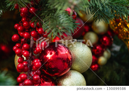 Christmas tree with red and golden balls and lights garland. Xmas card. Close up. Winter. Outdoors. Christmas tree with red and golden balls and lights garland. Xmas card. Close up. Winter. Outdoors. 130899386