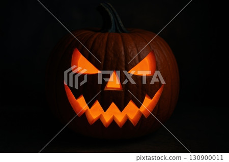 Carved pumpkin with glowing face in dark setting for Halloween celebration 130900011