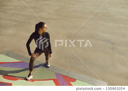 Female model in sportswear posing on sportsground during outdoor fitness workout in city Female model in sportswear posing on sportsground during outdoor fitness workout in city 130901054