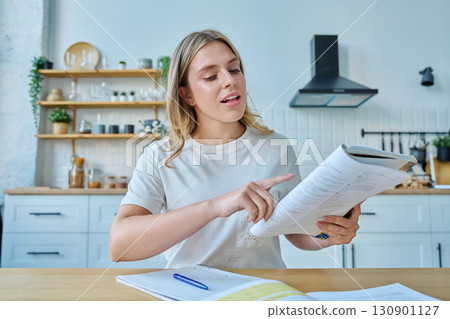 Webcam portrait female university student, sitting at home at the table with textbooks 130901127