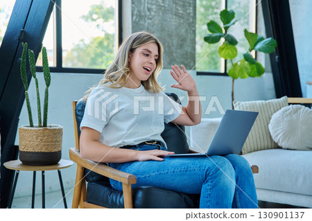 Young woman using laptop for video call, online chat conference sitting at home Young woman using laptop for video call, online chat conference sitting at home 130901137