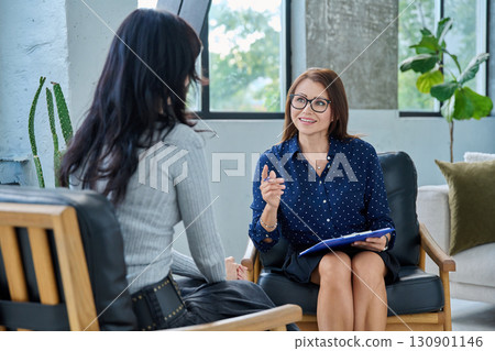 Smiling middle aged professional female psychologist, counselor working with young woman 130901146