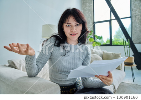 Web cam view of young woman with papers, online meeting, video call 130901160