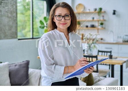 Portrait confident middle aged businesswoman posing with clipboard 130901183