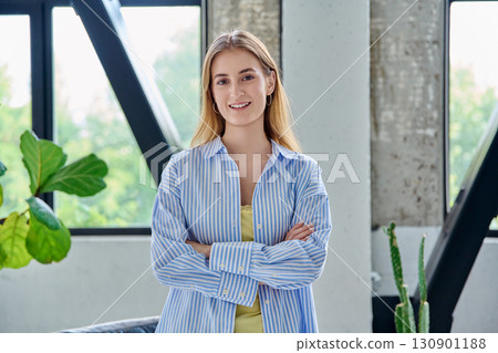 Portrait of smiling young female looking at camera with crossed arms in home 130901188