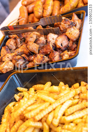 Sizzling street food feast: grilled sausages, shashlik, and golden french fries Sizzling street food feast: grilled sausages, shashlik, and golden french fries 130901233