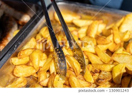 Freshly fried French fries served with tongs Freshly fried French fries served with tongs 130901243