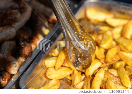 Freshly fried French fries served with tongs 130901244