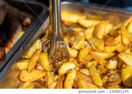 Freshly fried French fries served with tongs 130901245