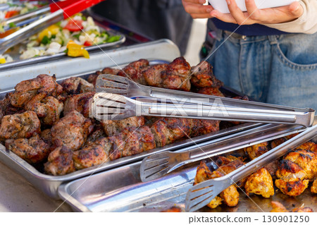 Sizzling street food feast: grilled sausages, shashlik, and golden french fries 130901250