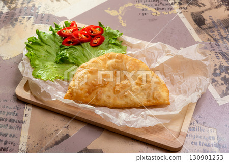 Freshly fried cheburek with lettuce and red pepper rings 130901253
