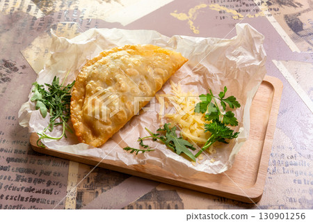 Golden brown cheburek pastry with cheese and arugula 130901256
