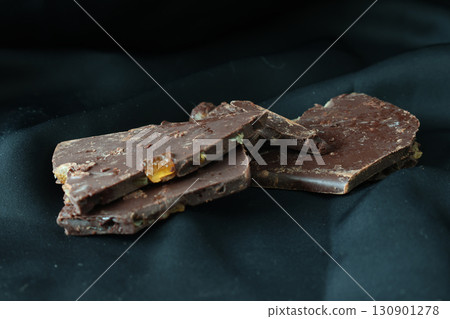 Stack of orange chocolates on a black background Stack of orange chocolates on a black background 130901278
