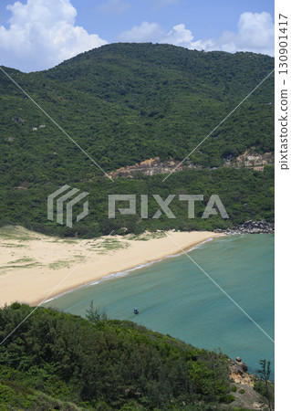 Bay surrounded by mountains with sandy beach and small fishing boat in South China Sea in Vietnam 130901417