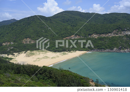 Bay surrounded by mountains with sandy beach and small fishing boat in South China Sea in Vietnam 130901418