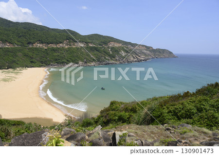 A bay surrounded by mountains with sandy beach and small fishing boat in South China Sea in Vietnam A bay surrounded by mountains with sandy beach and small fishing boat in South China Sea in Vietnam 130901473
