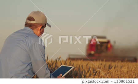 farmer working in wheat field, combine harvester ploughing in wheat field, agriculture tablet, innovations in agriculture, sustainable farming practices, maximizing harvest efficiency, connecting 130901521