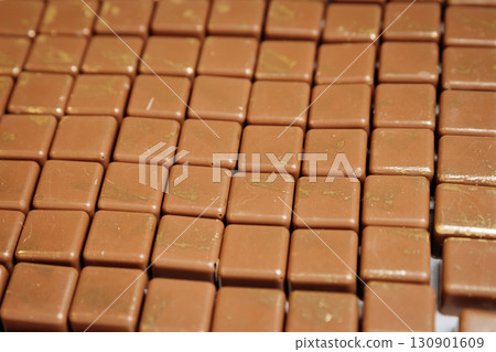 Luxury milk chocolates with golden details in a neat grid, gourmet artisan sweets Luxury milk chocolates with golden details in a neat grid, gourmet artisan sweets 130901609