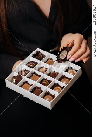 Luxury handmade chocolates in elegant box held by woman with manicured nails 130901614