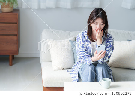 Depressed young woman holding a smartphone Depressed young woman holding a smartphone 130902275
