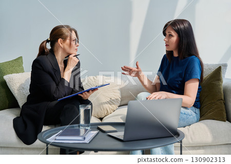 Female patient talking to psychotherapist psychologist, sitting together in office Female patient talking to psychotherapist psychologist, sitting together in office 130902313