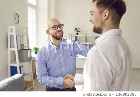 Two business men standing in office making deal shaking hands celebrating business achievement. 130902385