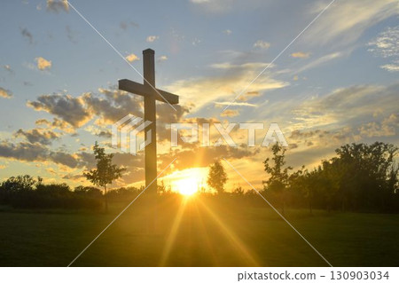 A large Christian cross in the landscape. A Christian cross illuminated by the sunset or sunrise. The concept of Christianity, spirituality, and enlightenment. 130903034