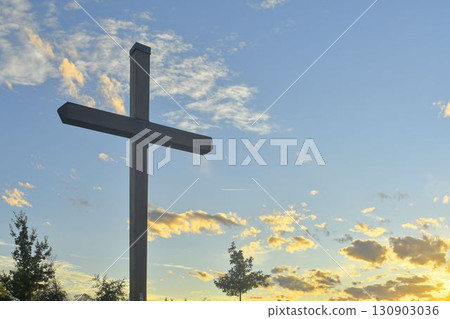 A large Christian cross in the landscape. A Christian cross illuminated by the sunset. The concept of Christianity, spirituality, and the concept of enlightenment. A large Christian cross in the landscape. A Christian cross illuminated by the sunset. The concept of Christianity, spirituality, and the concept of enlightenment. 130903036
