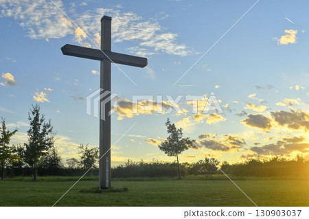 A large Christian cross in the countryside. A Christian cross illuminated by the setting sun. The concept of Christianity, spirituality, and liberation. A large Christian cross in the countryside. A Christian cross illuminated by the setting sun. The concept of Christianity, spirituality, and liberation. 130903037