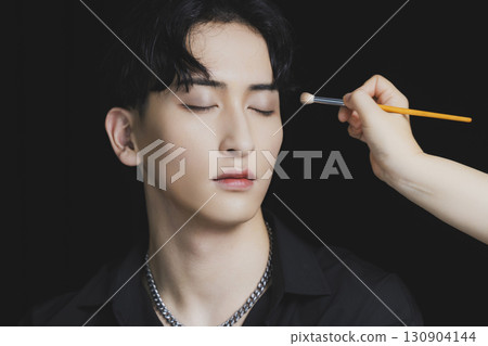 Young man putting on makeup Young man putting on makeup 130904144