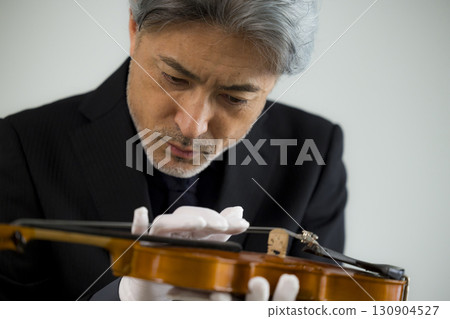 Senior man maintaining a violin 130904527
