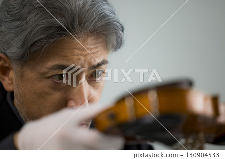 Senior man maintaining a violin Senior man maintaining a violin 130904533