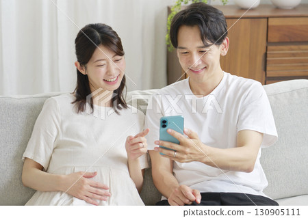 Pregnant wife and husband using smartphones in the living room 130905111