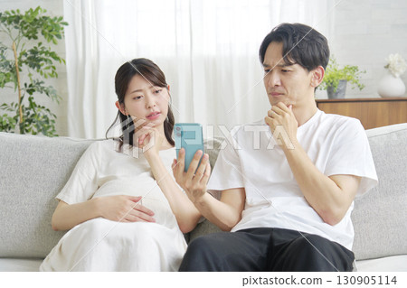 Pregnant wife and husband holding smartphones Pregnant wife and husband holding smartphones 130905114