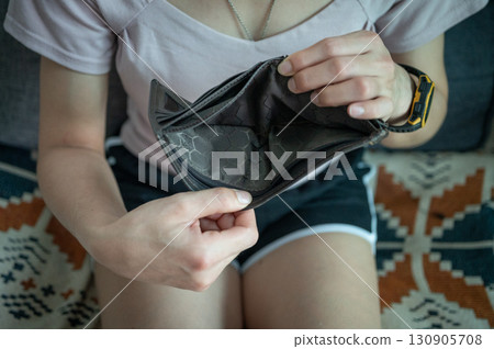 Cropped shot view of woman holding empty wallet. Having financial problems means being unable to pay debts over the short or long term. 130905708