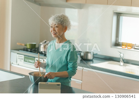 Elderly woman cooking for herself 130906541