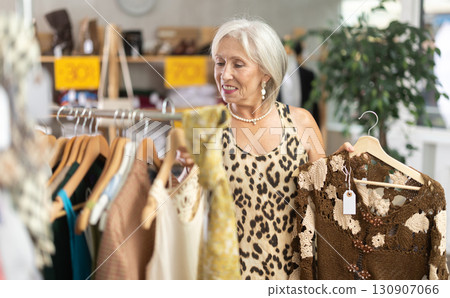 Positive mature woman choosing something for summer in clothing store Positive mature woman choosing something for summer in clothing store 130907066