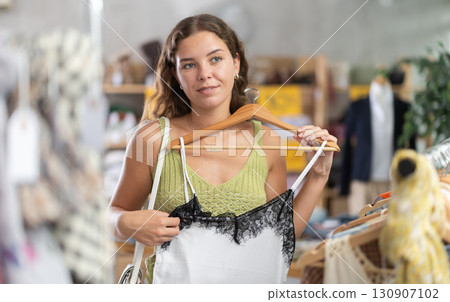 Young woman chooses a set of clothes for the summer. Visitor to the boutique examines new summer collection of clothes 130907102