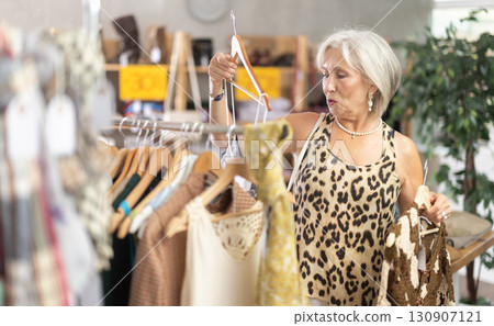 Elderly woman choosing summer clothes in store 130907121