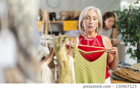 Attentive mature woman choosing something for summer in clothing store Attentive mature woman choosing something for summer in clothing store 130907123