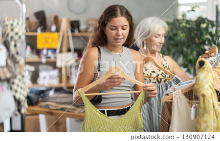 Two happy women of different ages choose summer clothes in fashion boutique Two happy women of different ages choose summer clothes in fashion boutique 130907124