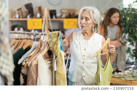 Elderly woman chooses top in clothing store 130907158