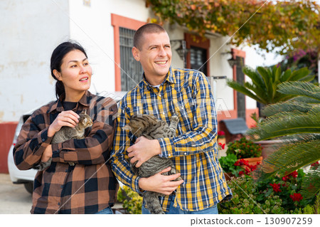Couple with kitties standing outdoors 130907259