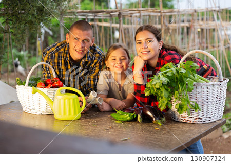 Family posing in garden with gathered vegetables Family posing in garden with gathered vegetables 130907324