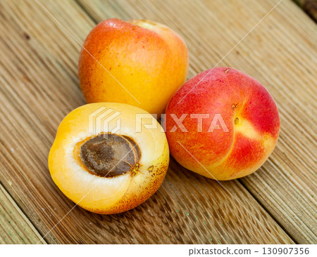 Image of ripe juicy apricots on wooden table in kitchen 130907356