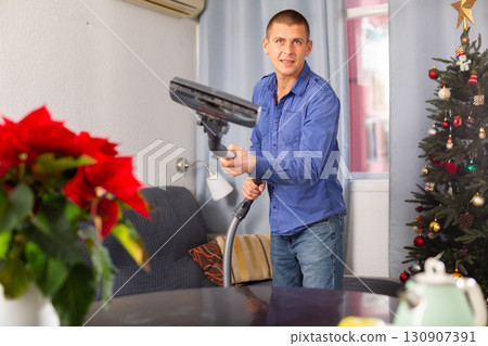 Man vacuuming room in his house before christmas 130907391